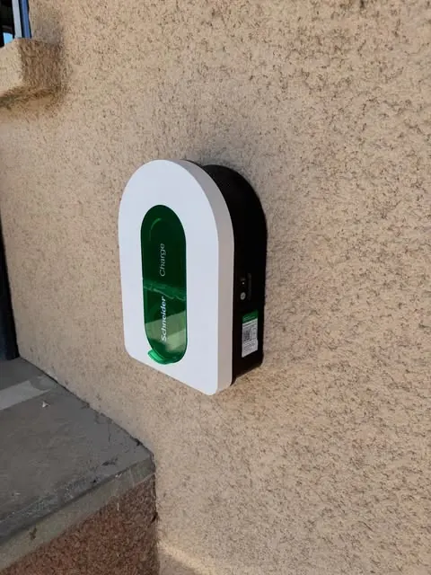 Borne de recharge Schneider Charge, blanche et verte, fixée sur un mur crépi