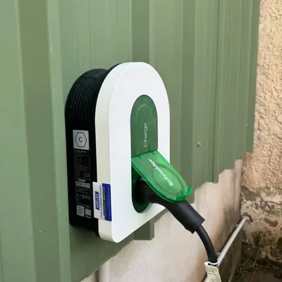 Borne Schneider Charge fixée sur un bardage vert, câble de recharge branché