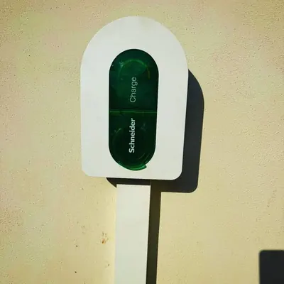 Borne de recharge Schneider Charge montée sur un pied, devant un mur jaune pâle