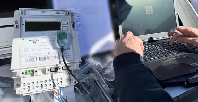 Compteur électrique et ordinateur portable pendant une mise en service, mains d'un technicien au clavier